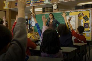 老师站在教室前面，学生举手